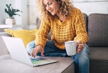 Woman working on laptop drinking coffee