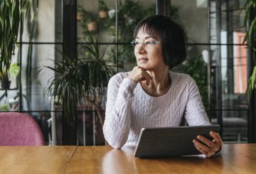 woman in her 60s using tablet with hand on chin