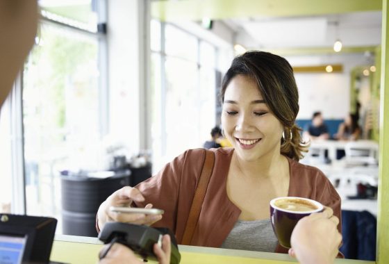 Woman using her phone to make payment in a cafe