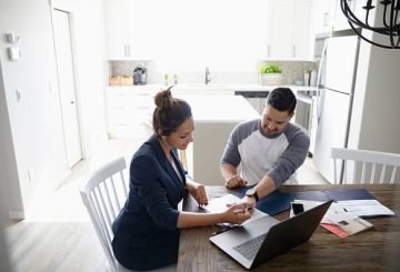 Young couple using computer at kitchen table