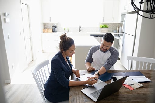 Young couple using computer at kitchen table