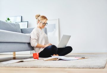 Female student sitting on floor of her apartment with laptop