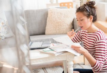 Woman reading bills while working on computer