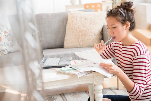 Woman reading bills while working on computer