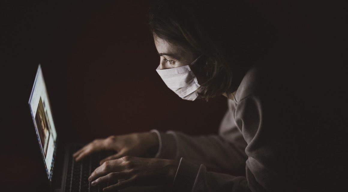 Woman wearing a mask and using laptop