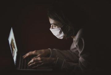 Woman wearing a mask and using laptop