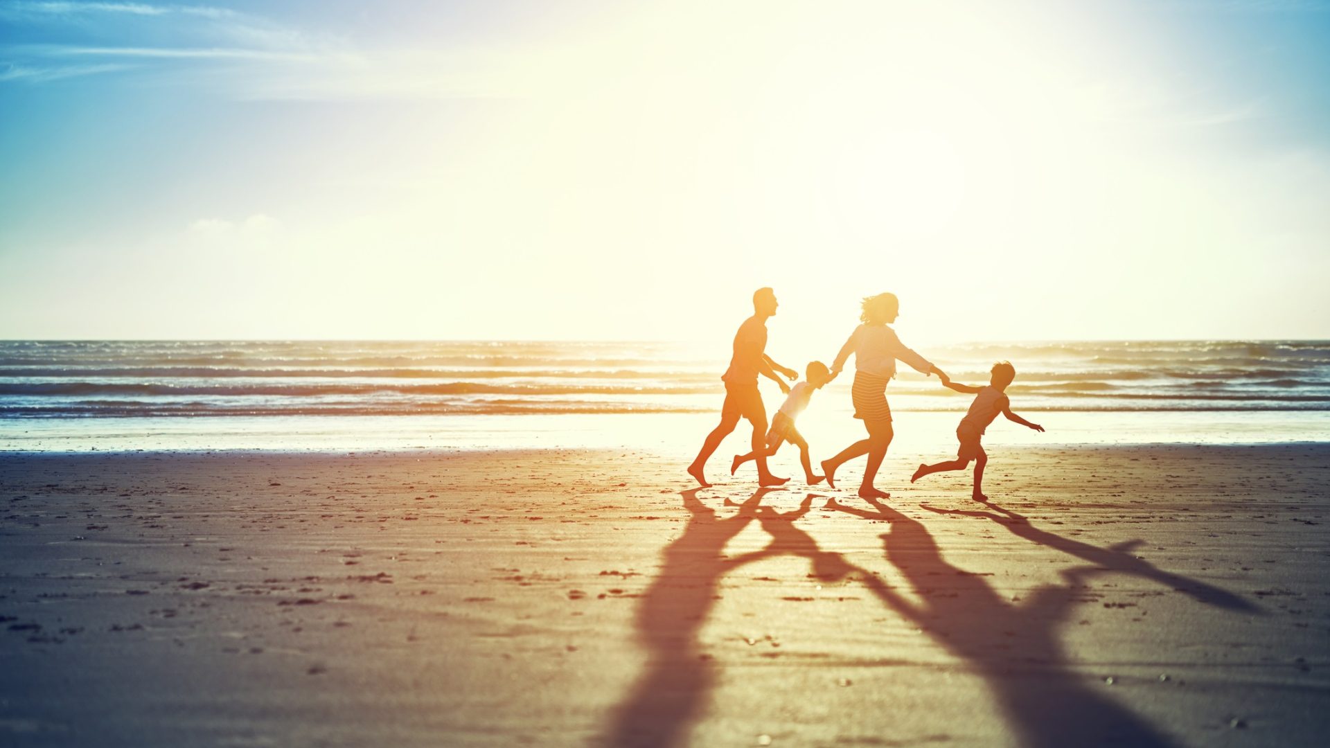 Shot of a carefree family of four enjoying a run on the beach