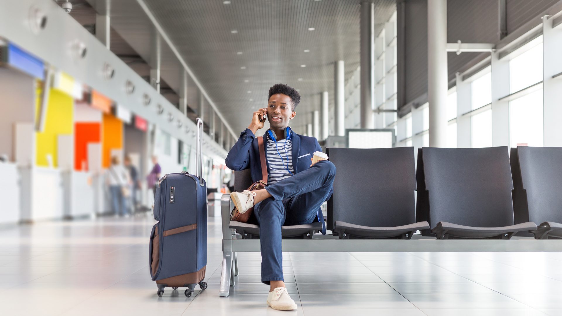 Young man talking on phone at airport lounge