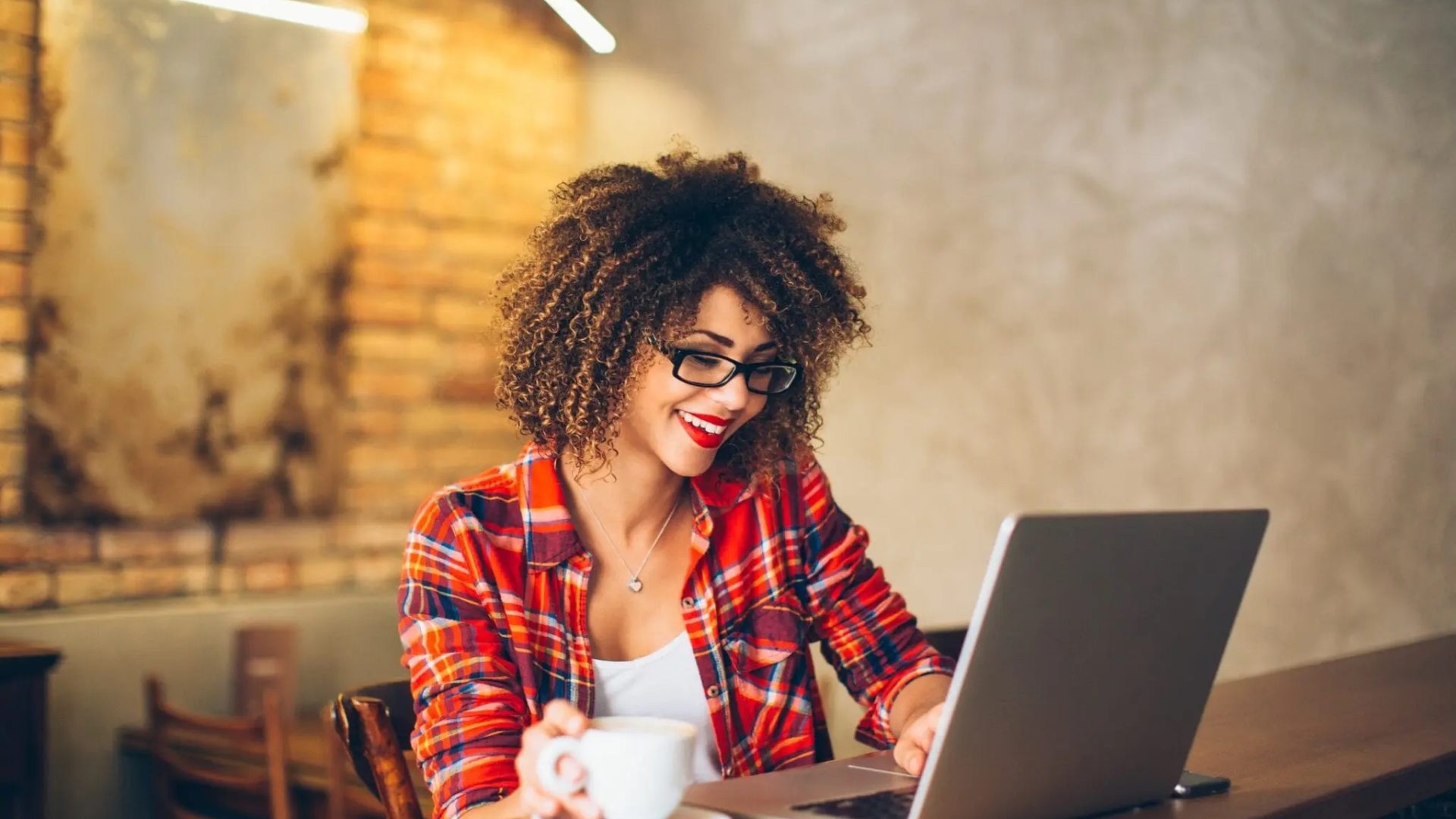 woman looking at computer and drinking coffee