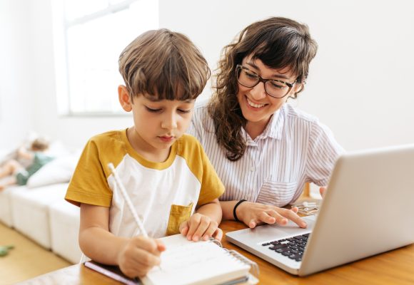 Boy doing homework with mother working