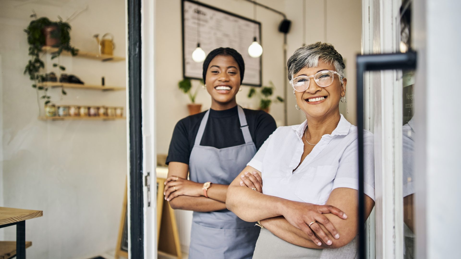 Coffee shop, senior woman manager portrait with barista feeling happy about shop success. Female server, waitress and small business owner together proud of cafe and bakery growth with a smile