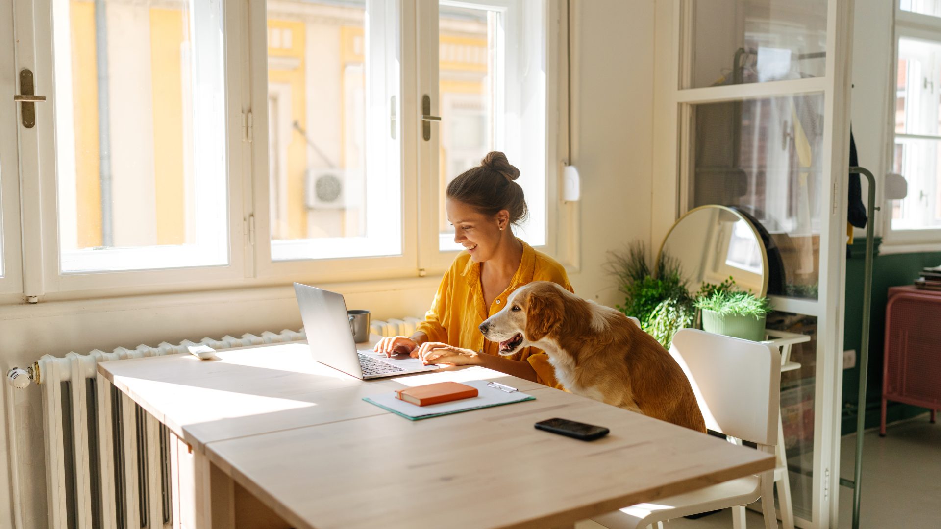 Photo of a young woman who is working from her home office, having the cutest and the cuddliest asistent - her pet dog