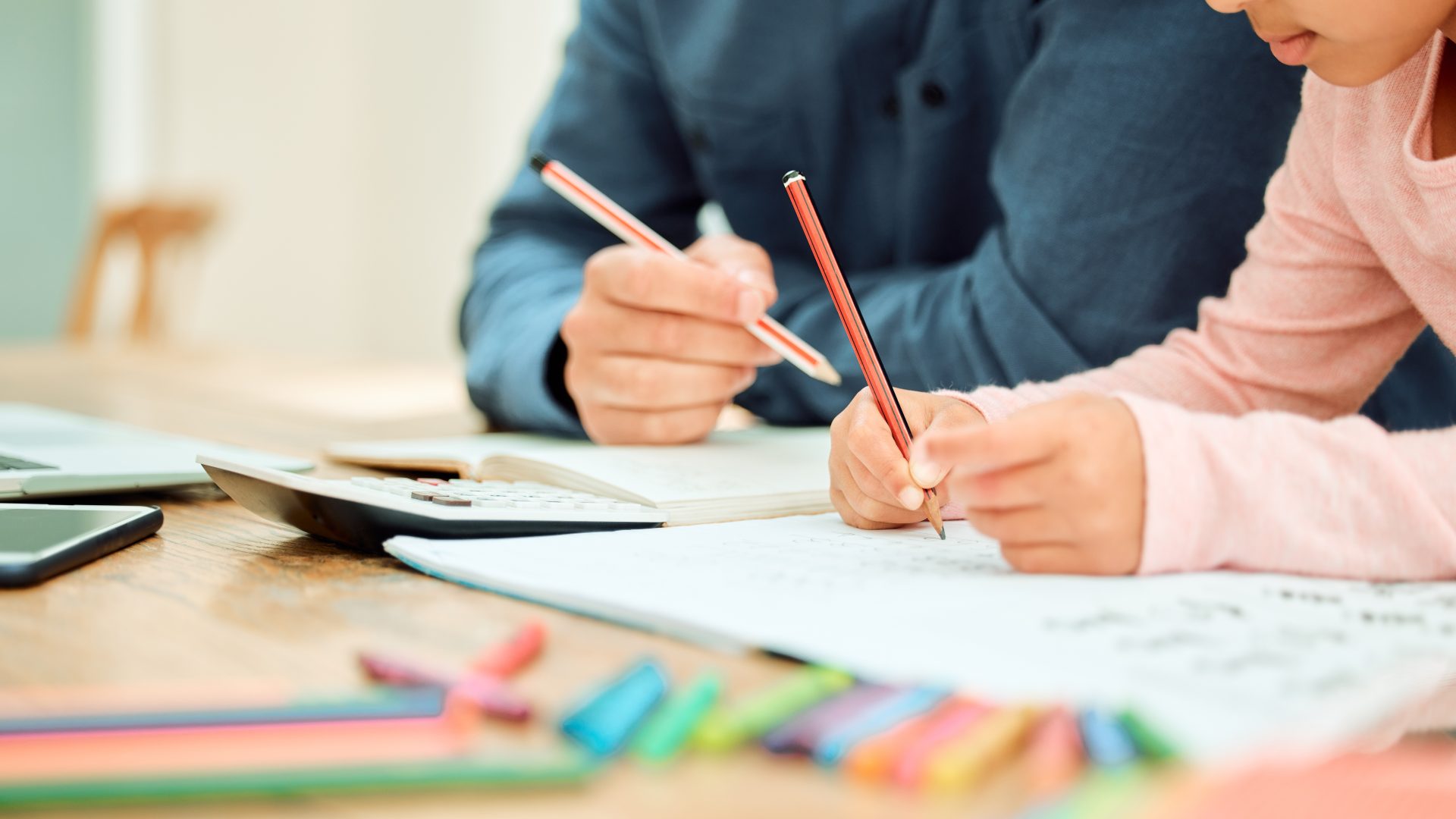 Cropped shot of an unrecognizable little girl doing her homework with some help from her dad