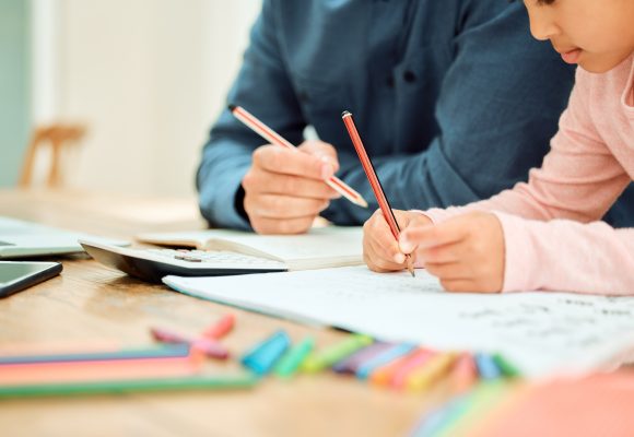 Cropped shot of an unrecognizable little girl doing her homework with some help from her dad