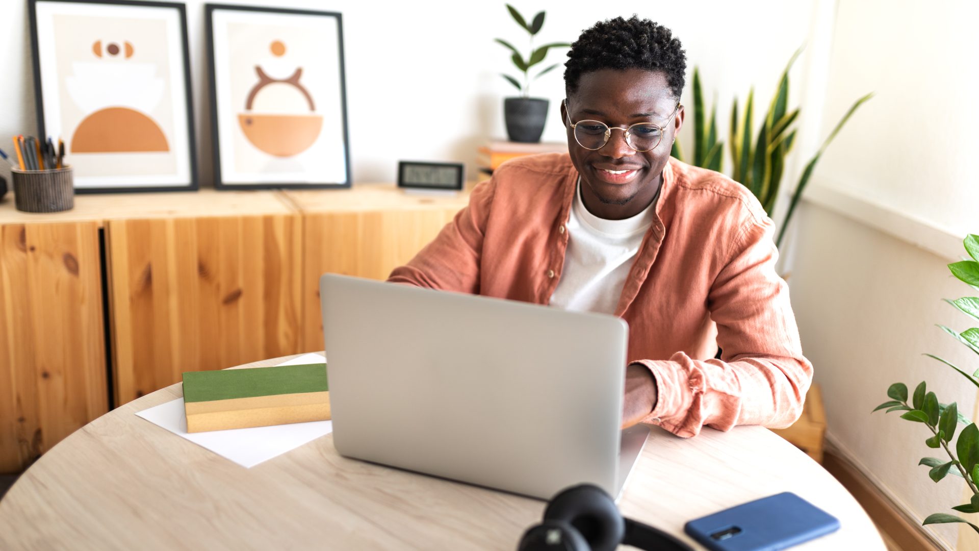 Happy black male university student studying at home using laptop.