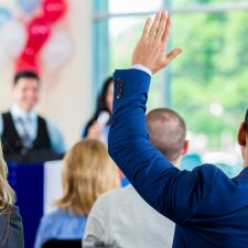 Hispanic man raising hand during political town hall meeting