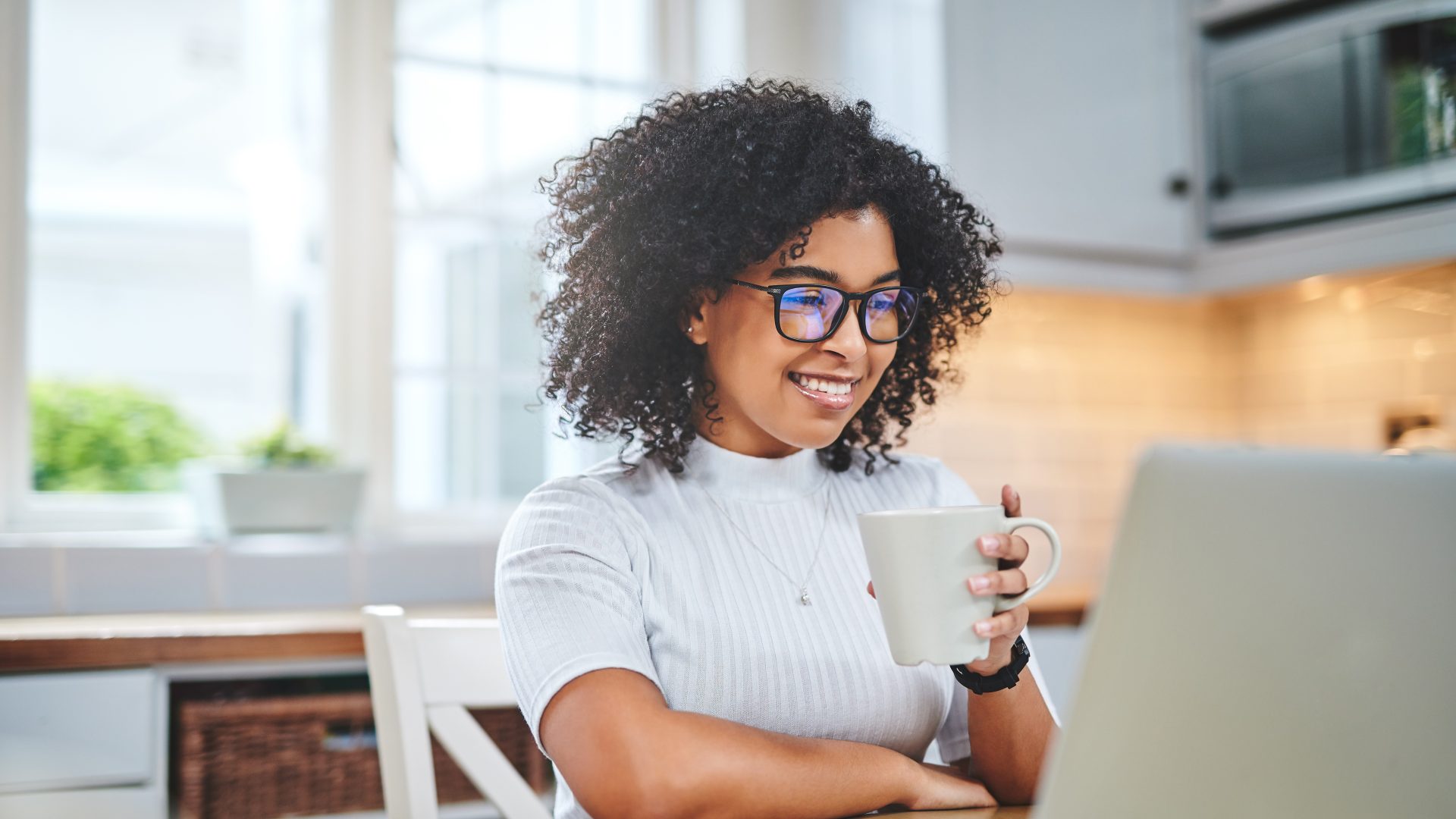 Shot of a young woman using a laptop and having coffee while working from