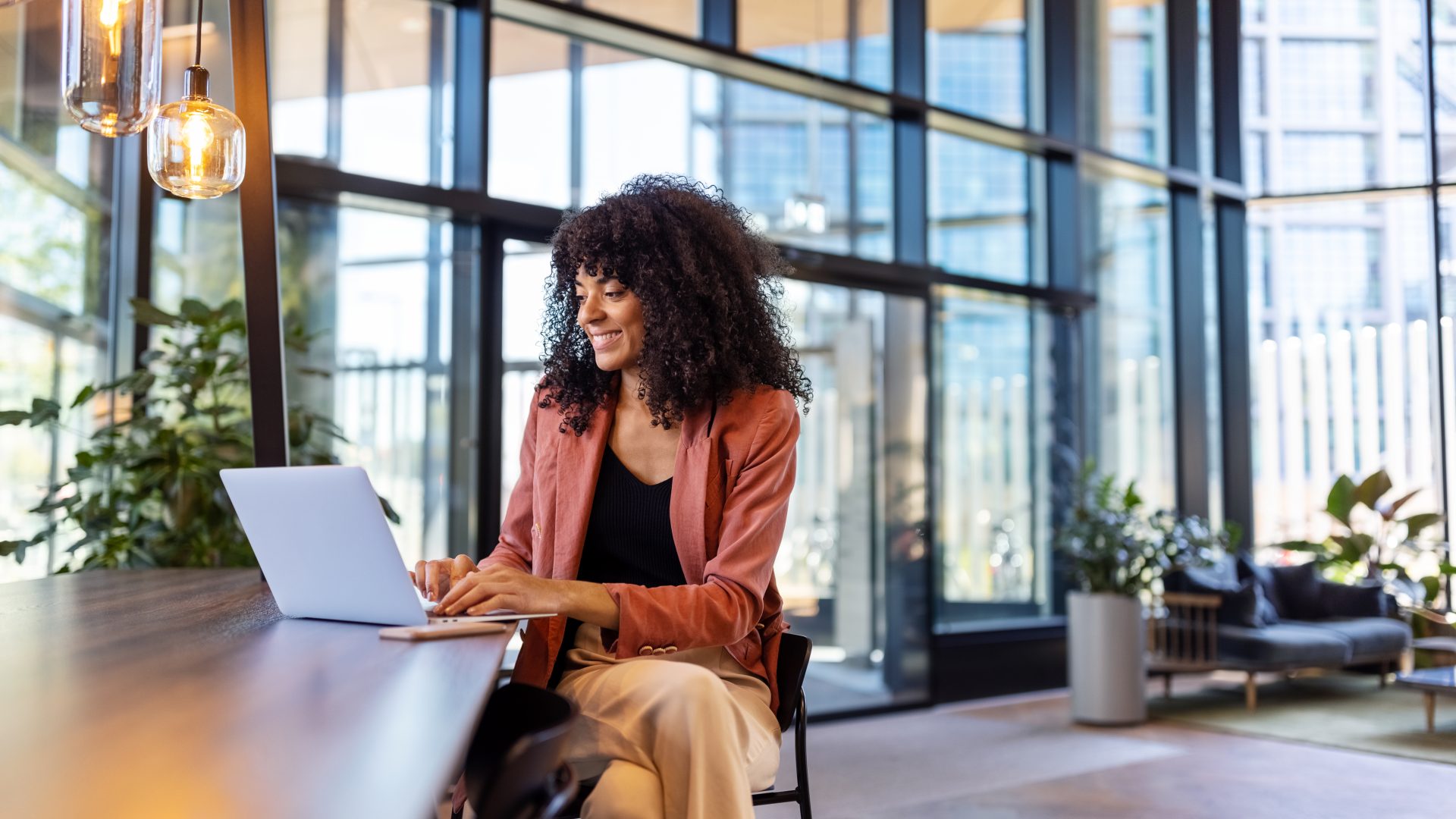 Young African woman working on laptop at office cafe