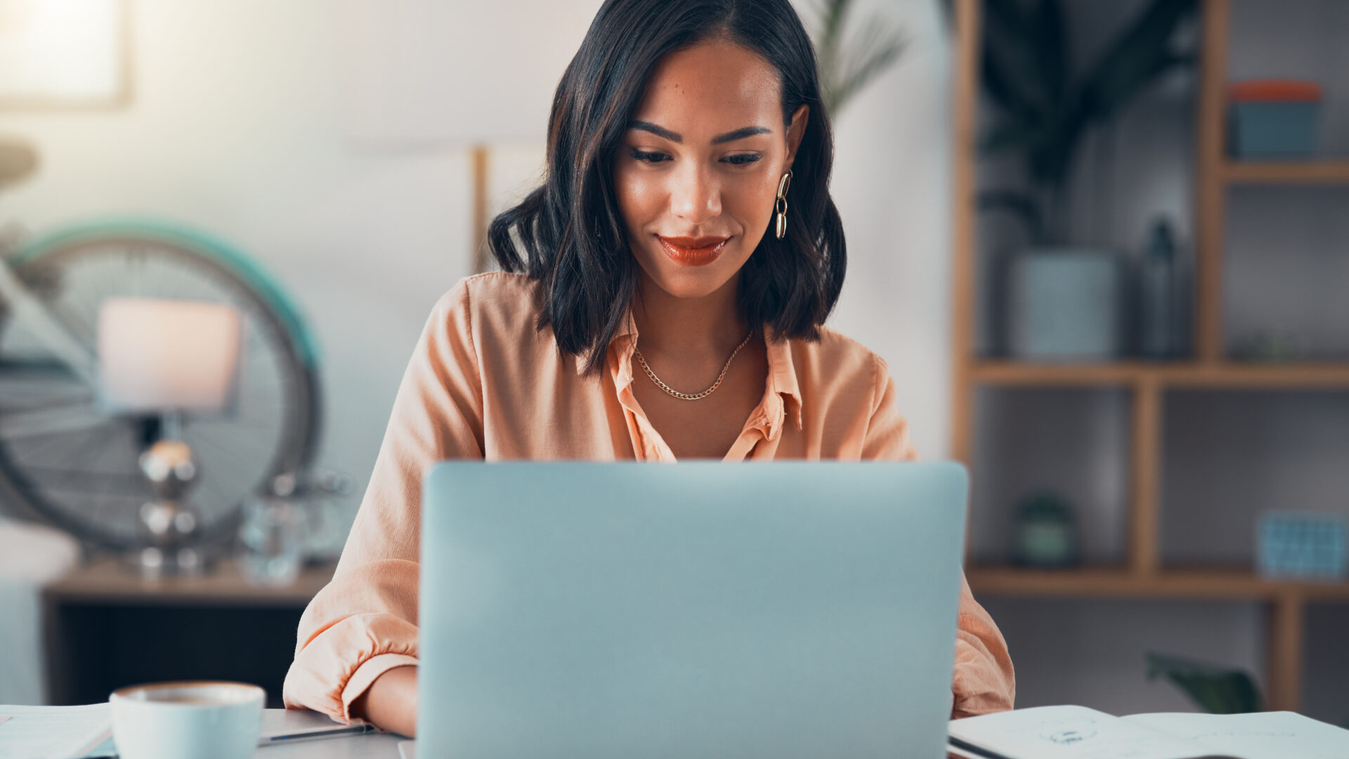 Woman working on laptop online, checking emails and planning on the internet while sitting in an office alone at work