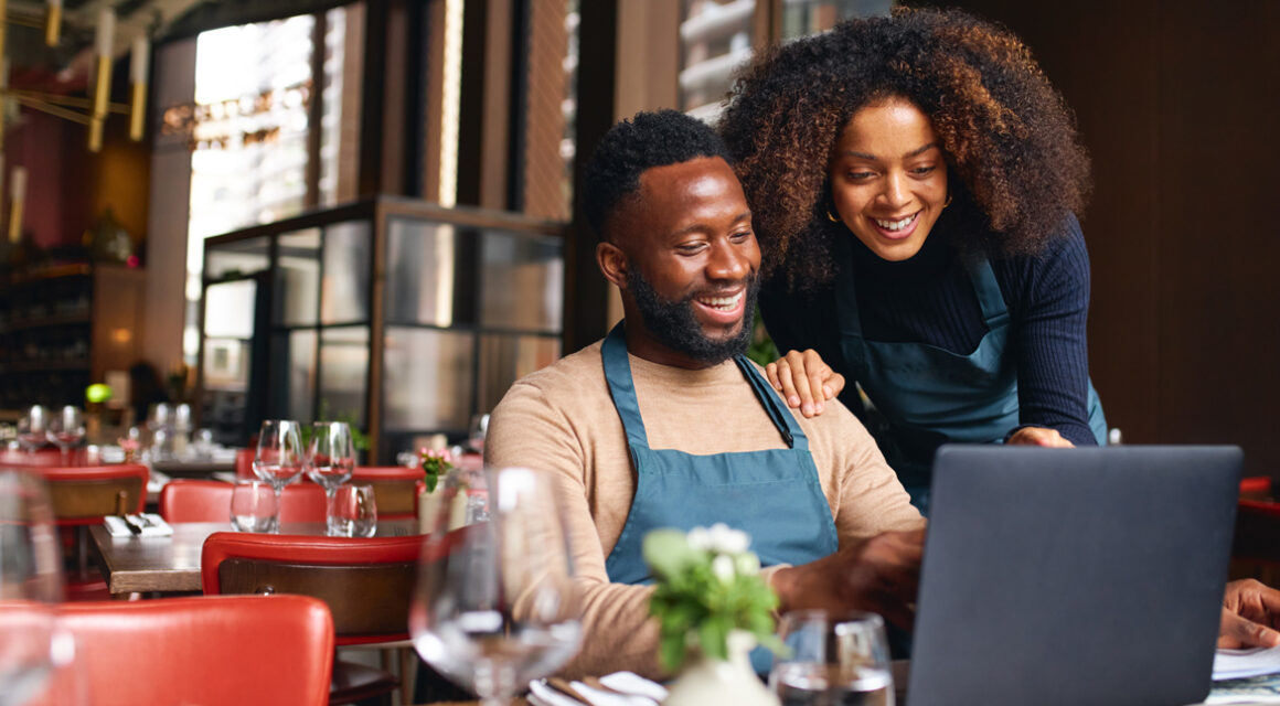 smiling business owners looking at computer