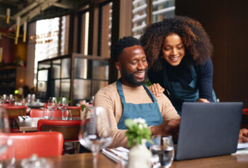 smiling business owners looking at computer